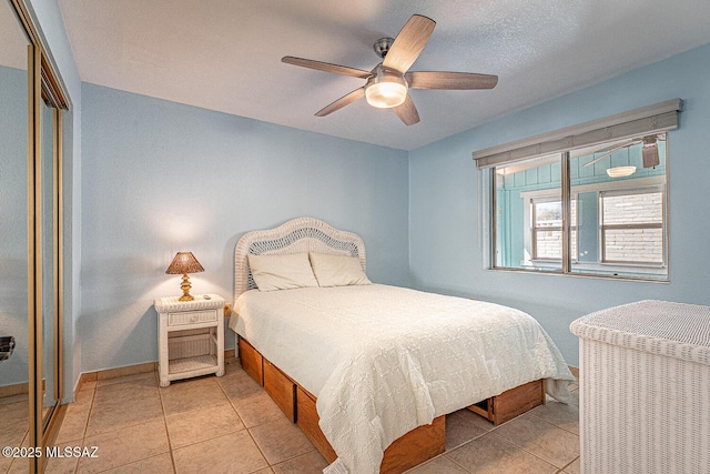 bedroom featuring light tile patterned floors, a closet, and ceiling fan