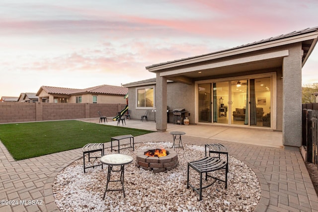 back house at dusk featuring a patio area, a yard, and a fire pit