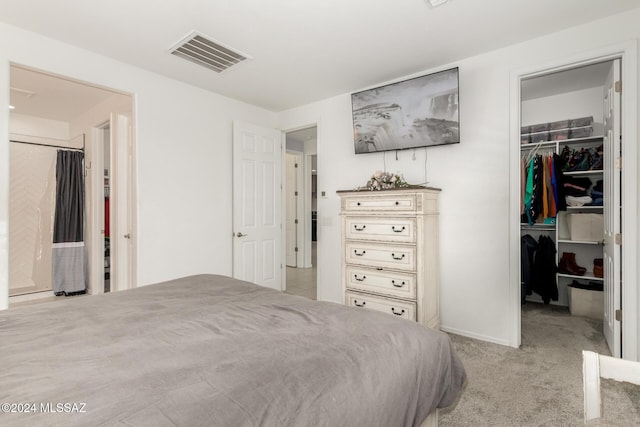 carpeted bedroom with a walk in closet and a closet