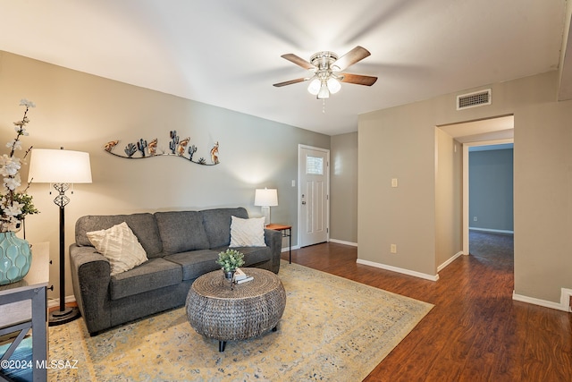 living room featuring ceiling fan and dark wood-type flooring