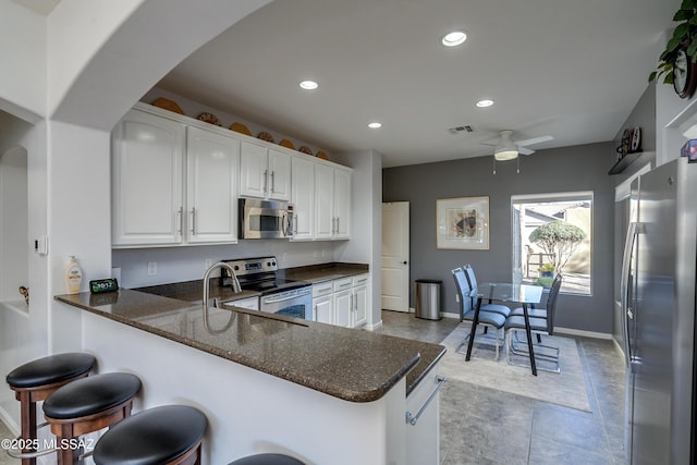 kitchen featuring ceiling fan, appliances with stainless steel finishes, kitchen peninsula, and white cabinets