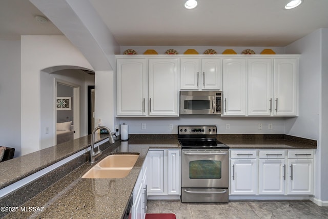 kitchen featuring white cabinetry, sink, stainless steel appliances, and dark stone countertops