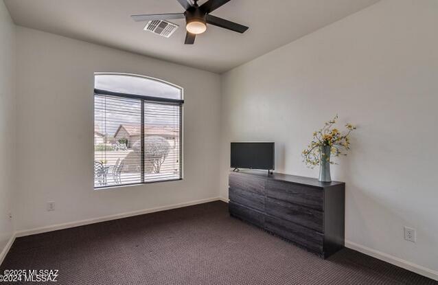 unfurnished bedroom with dark carpet and ceiling fan