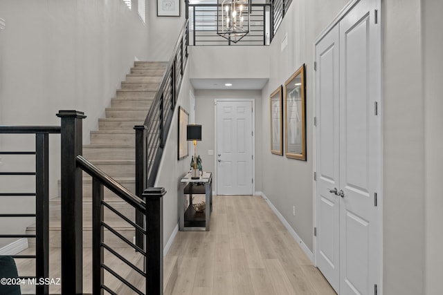 entrance foyer with light hardwood / wood-style floors, a high ceiling, and an inviting chandelier