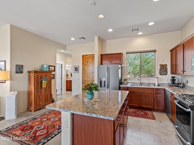 kitchen featuring a center island, sink, light stone countertops, light tile patterned floors, and stainless steel appliances