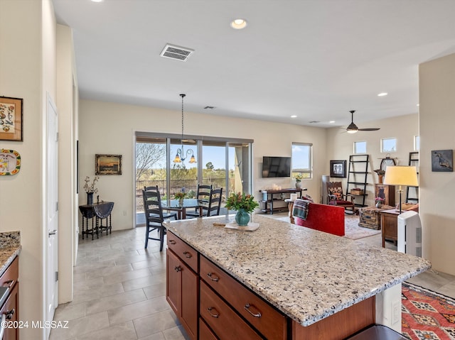 kitchen featuring ceiling fan with notable chandelier, pendant lighting, a center island, and plenty of natural light