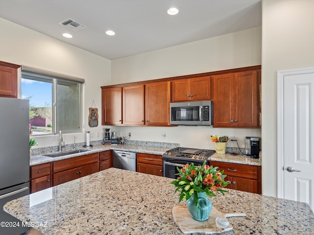 kitchen with light stone countertops, sink, and appliances with stainless steel finishes