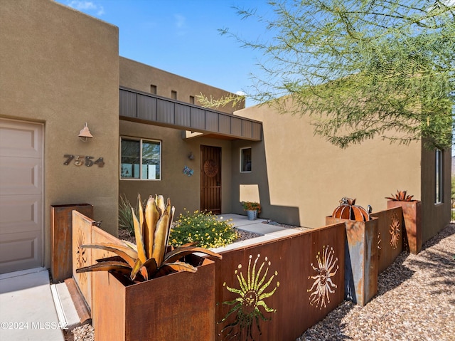 doorway to property featuring stucco siding and a garage