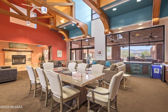 carpeted dining area with a tiled fireplace and a towering ceiling