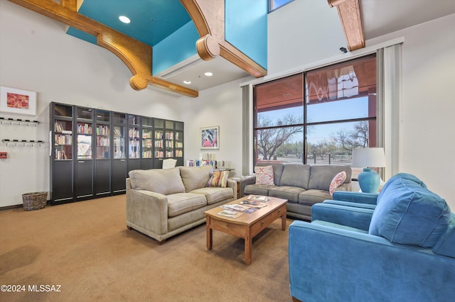 carpeted living room with beam ceiling and a high ceiling