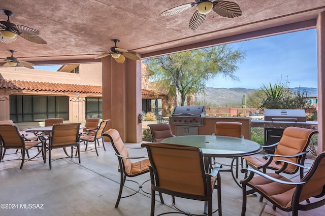 view of patio / terrace featuring a mountain view, ceiling fan, grilling area, and an outdoor kitchen