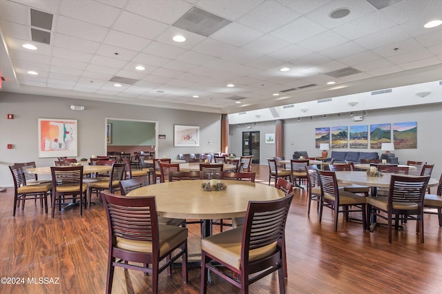 dining area with a drop ceiling and dark hardwood / wood-style floors