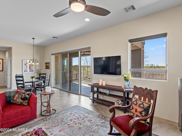 tiled living room with ceiling fan with notable chandelier