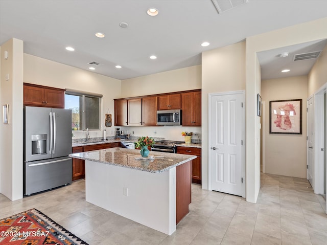 kitchen with a center island, sink, light stone counters, light tile patterned floors, and appliances with stainless steel finishes