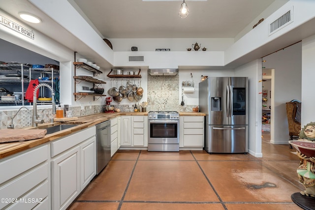 kitchen with stainless steel appliances, visible vents, a sink, and wood counters