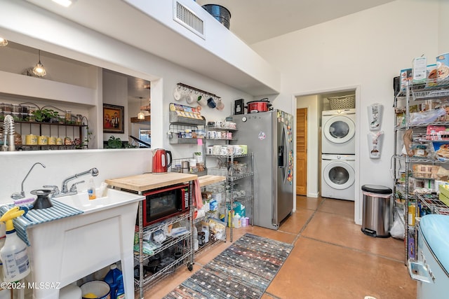 kitchen featuring stainless steel refrigerator with ice dispenser, stacked washing maching and dryer, and pendant lighting