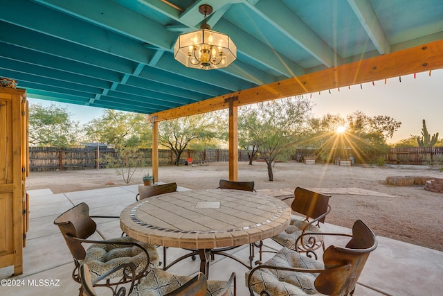 patio terrace at dusk with outdoor dining area and a fenced backyard