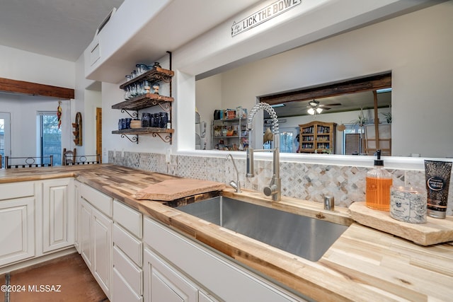 kitchen featuring a sink, wood counters, white cabinets, open shelves, and tasteful backsplash