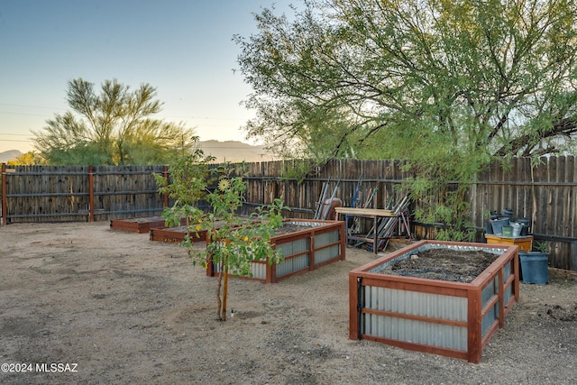 yard at dusk with fence and a vegetable garden