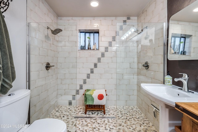 full bath with toilet, a tile shower, and a sink