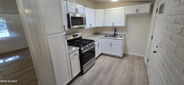 kitchen featuring white cabinets, light hardwood / wood-style floors, sink, and appliances with stainless steel finishes