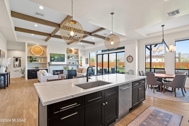 kitchen featuring dishwasher, decorative light fixtures, a kitchen island with sink, and sink