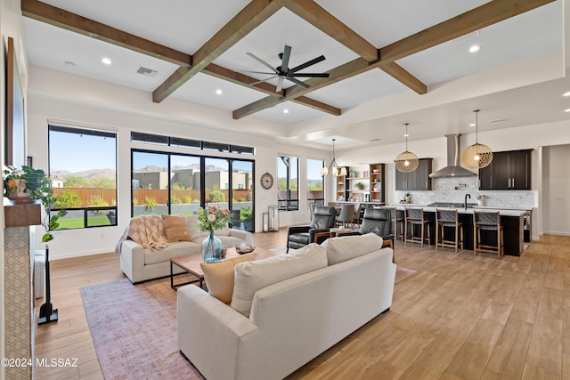 living area with light wood-style flooring, coffered ceiling, visible vents, baseboards, and beamed ceiling