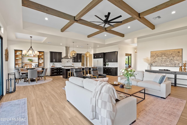 living room with beam ceiling, ceiling fan with notable chandelier, light hardwood / wood-style floors, and coffered ceiling