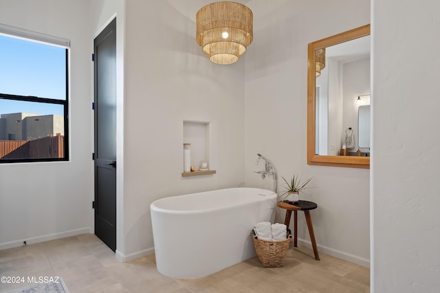 full bath featuring a freestanding tub, baseboards, and an inviting chandelier