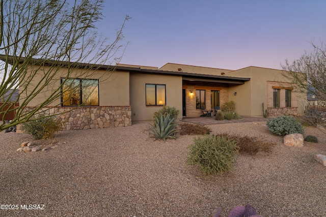 back of property at dusk with a patio and stucco siding