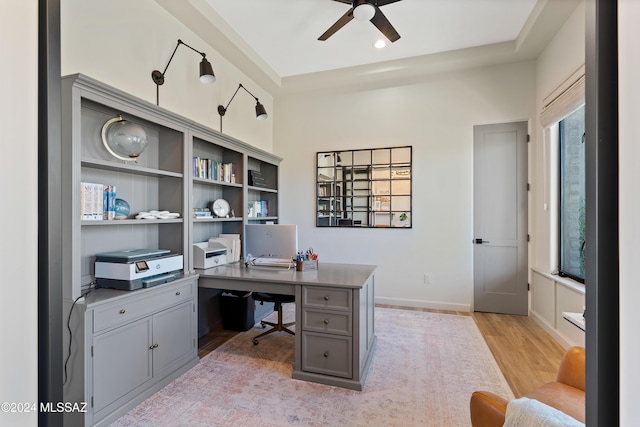 office area with light wood-type flooring, ceiling fan, and baseboards