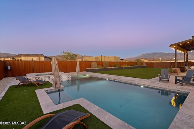 pool at dusk with a patio, a fenced backyard, a mountain view, an in ground hot tub, and a fenced in pool