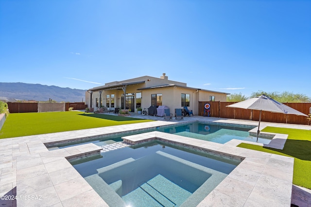 view of pool featuring an in ground hot tub, a patio, grilling area, a mountain view, and a yard