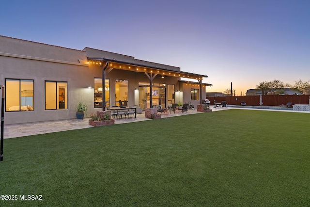 back of house with a yard, a patio area, fence, and stucco siding