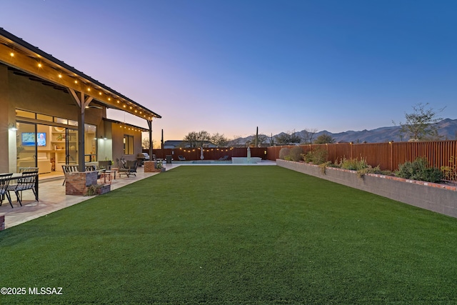 view of yard featuring a patio area, a fenced backyard, and a mountain view