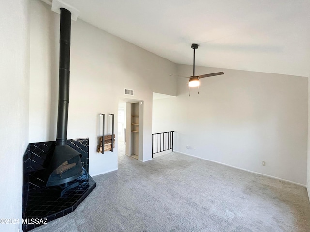 living room featuring carpet, ceiling fan, a wood stove, and high vaulted ceiling