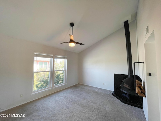 unfurnished living room featuring light carpet, a wood stove, vaulted ceiling, and ceiling fan