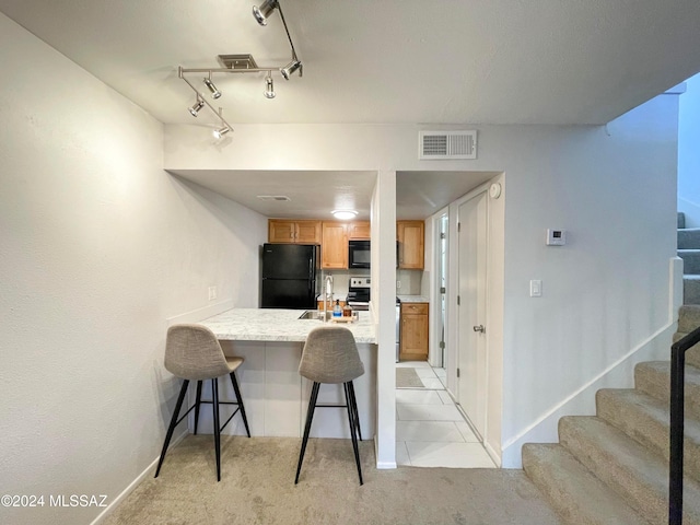 kitchen featuring sink, kitchen peninsula, light carpet, a breakfast bar, and black appliances