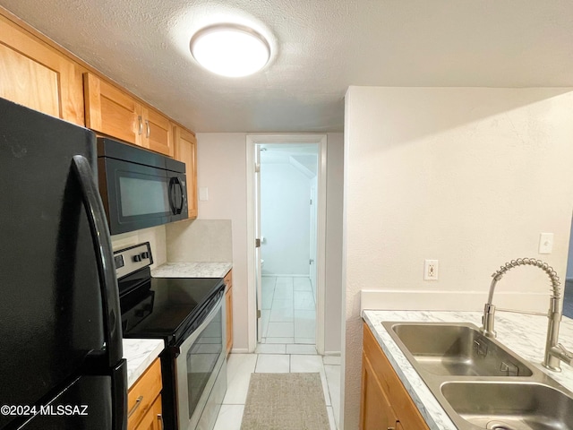 kitchen with sink, light tile patterned flooring, black appliances, and a textured ceiling