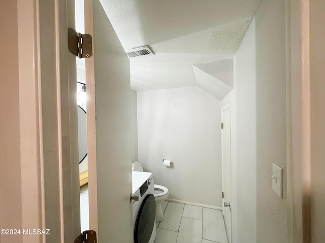 bathroom with toilet, vanity, a textured ceiling, and washer / dryer