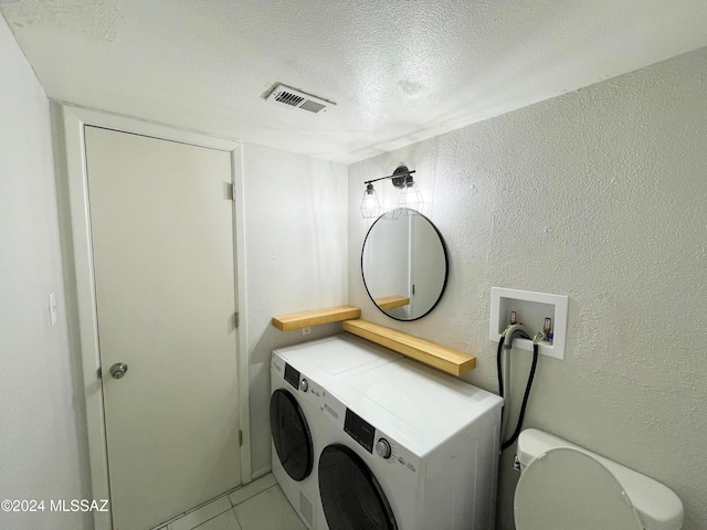 washroom with a textured ceiling, tile patterned floors, and washing machine and dryer