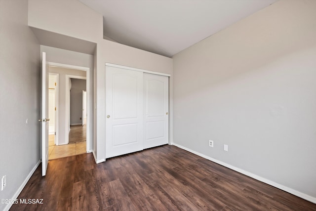 unfurnished bedroom featuring dark wood-style floors, a closet, and baseboards