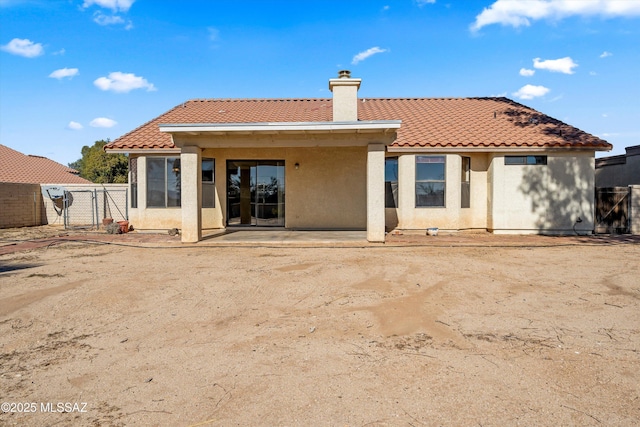 back of property with a patio, fence, a tiled roof, stucco siding, and a chimney