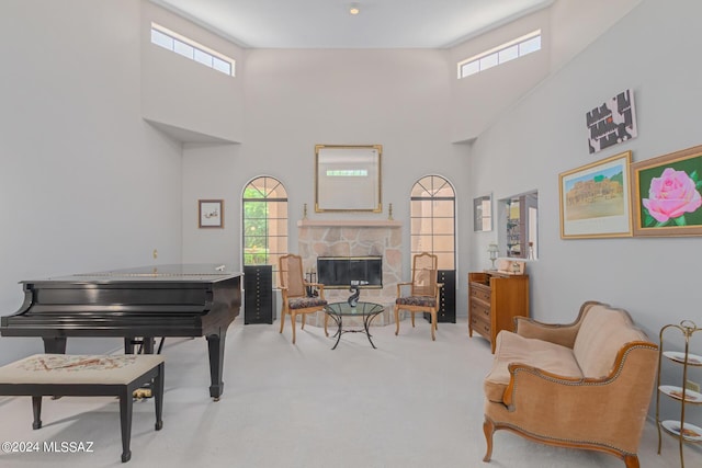 sitting room featuring light carpet, a high ceiling, plenty of natural light, and a fireplace