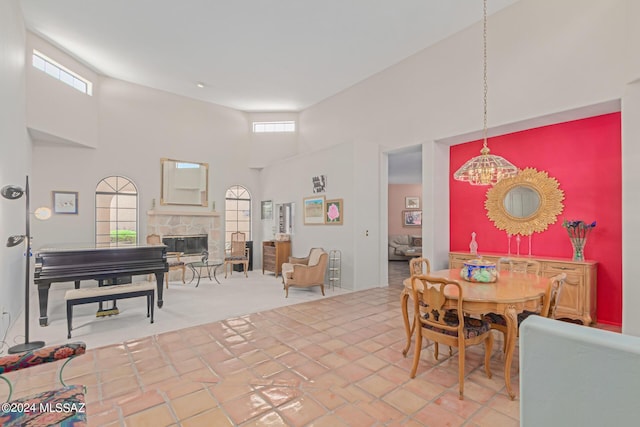 tiled dining space featuring a fireplace and a towering ceiling