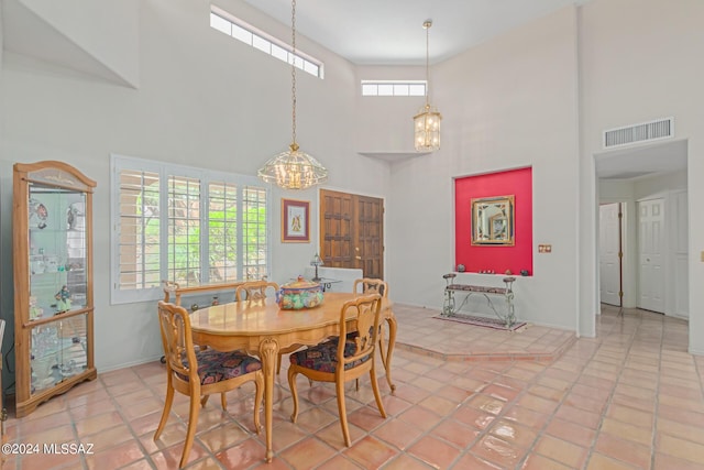 tiled dining area with a towering ceiling and a notable chandelier