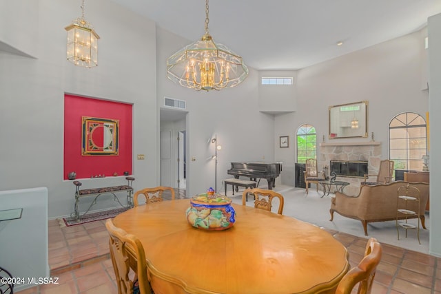 dining room with a fireplace, light tile patterned floors, and a towering ceiling