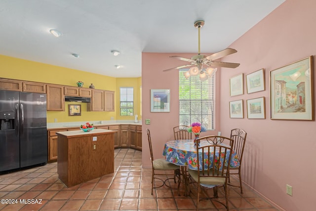 kitchen with stainless steel fridge, ceiling fan, stovetop, a kitchen island, and light tile patterned flooring