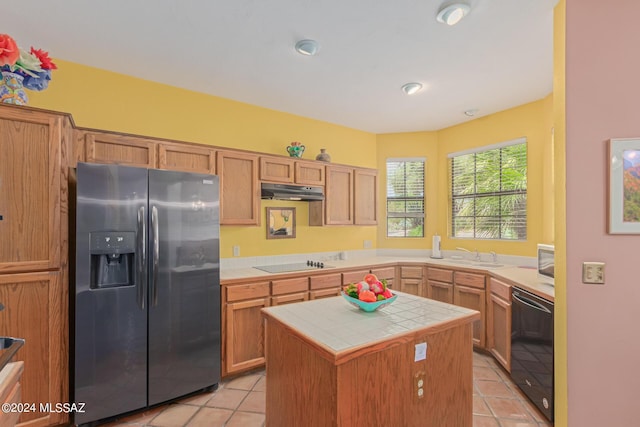 kitchen featuring tile countertops, a kitchen island, black appliances, and light tile patterned floors