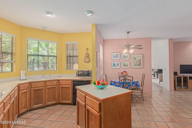 kitchen with tile countertops, a kitchen island, light tile patterned floors, and black dishwasher